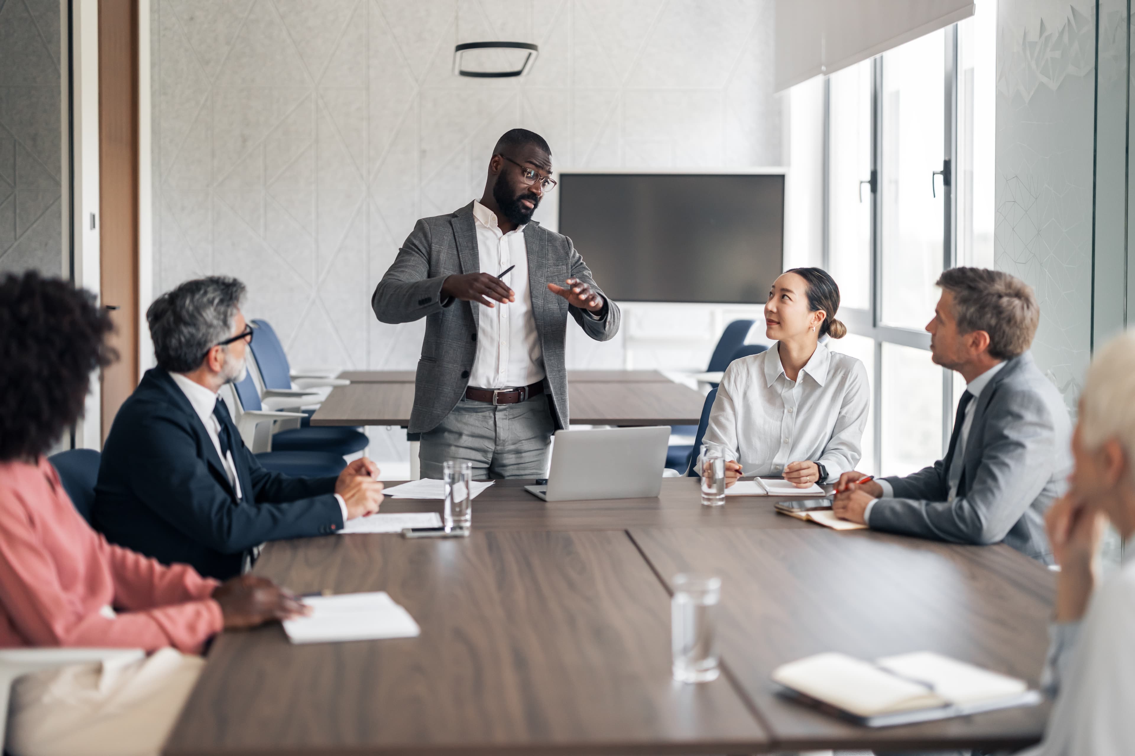 colleagues seated around a boardroom table AdobeStock 1887054253