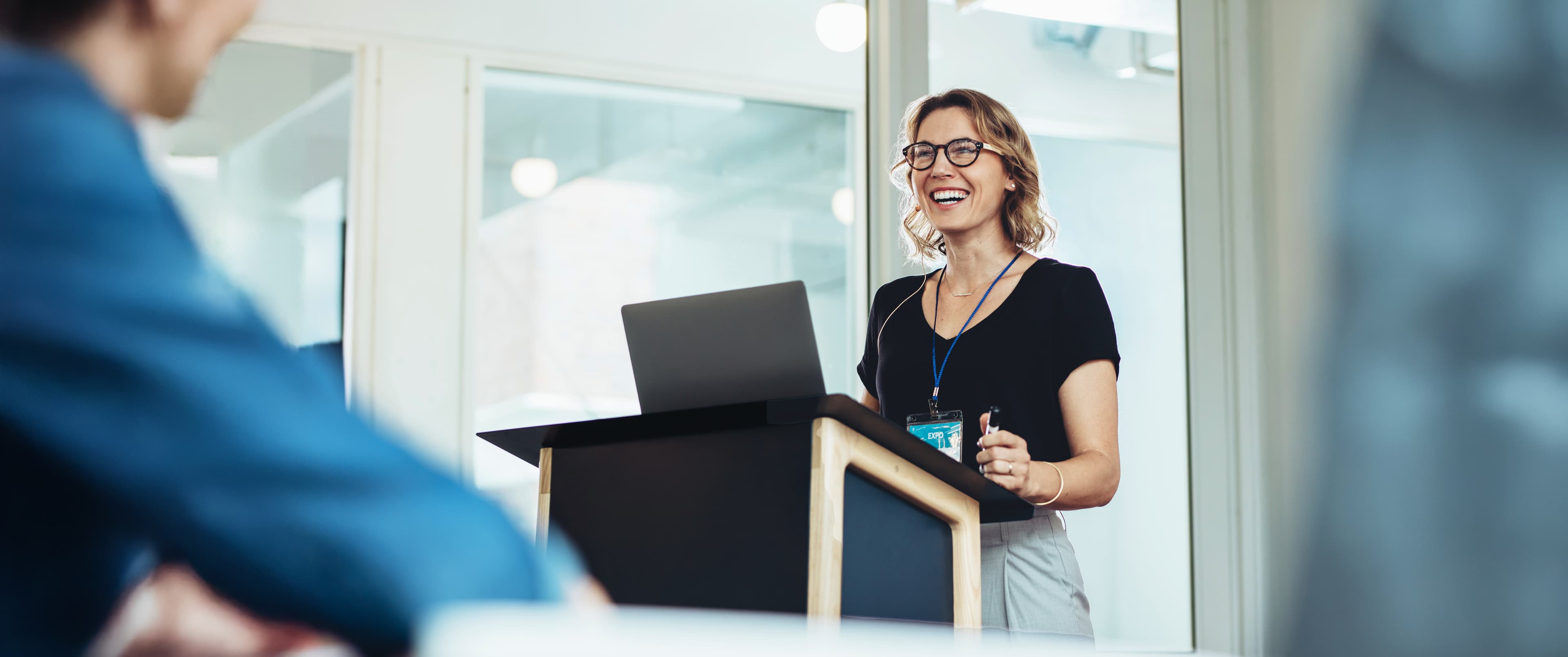 woman at a podium with a laptop AdobeStock 1691931200