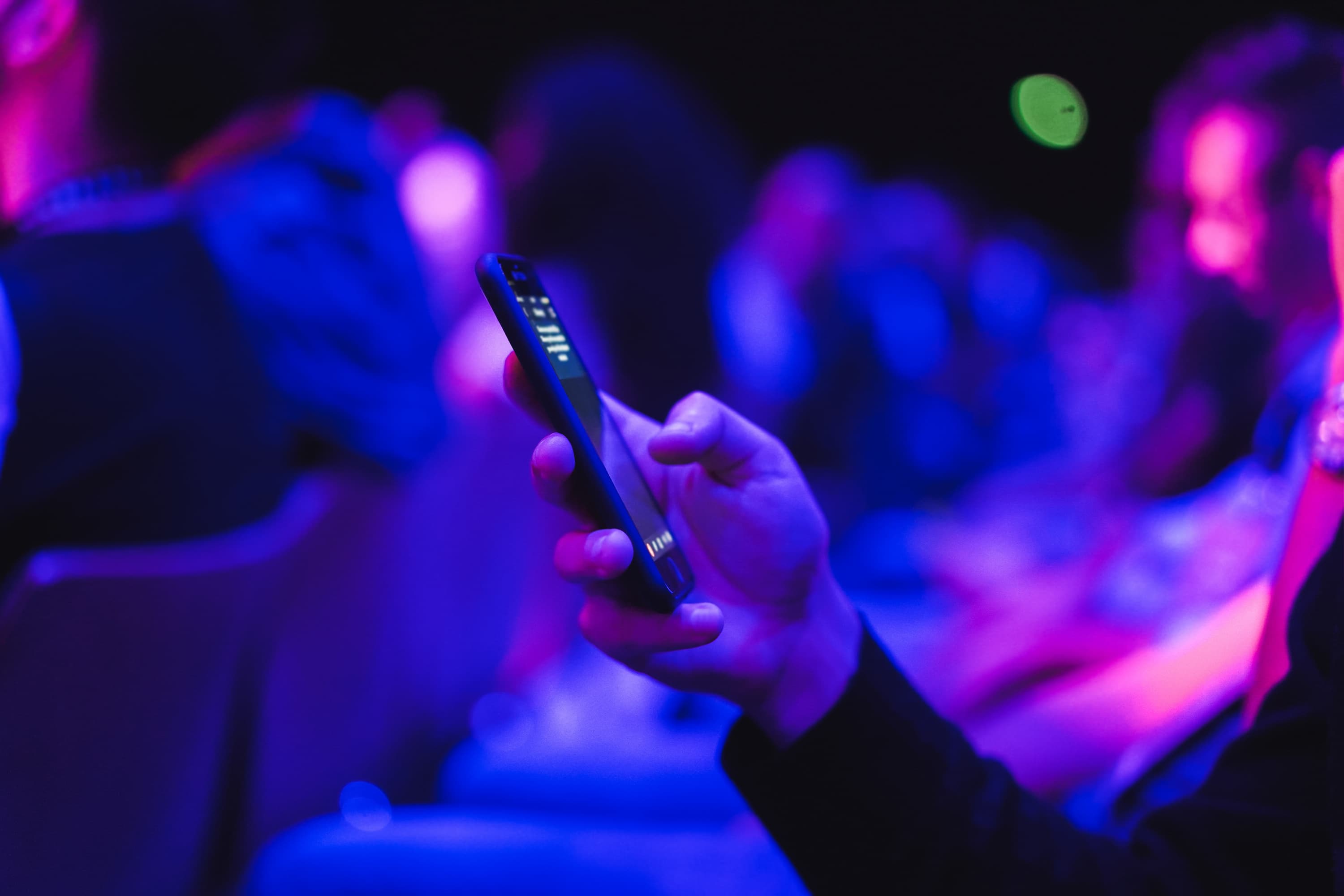 Person using a smartphone to book a community venue, with a crowd in the background