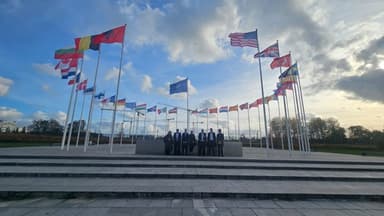 Group of delegates standing among EU and international flags in Brussels, reflecting engagement with European cyber policy