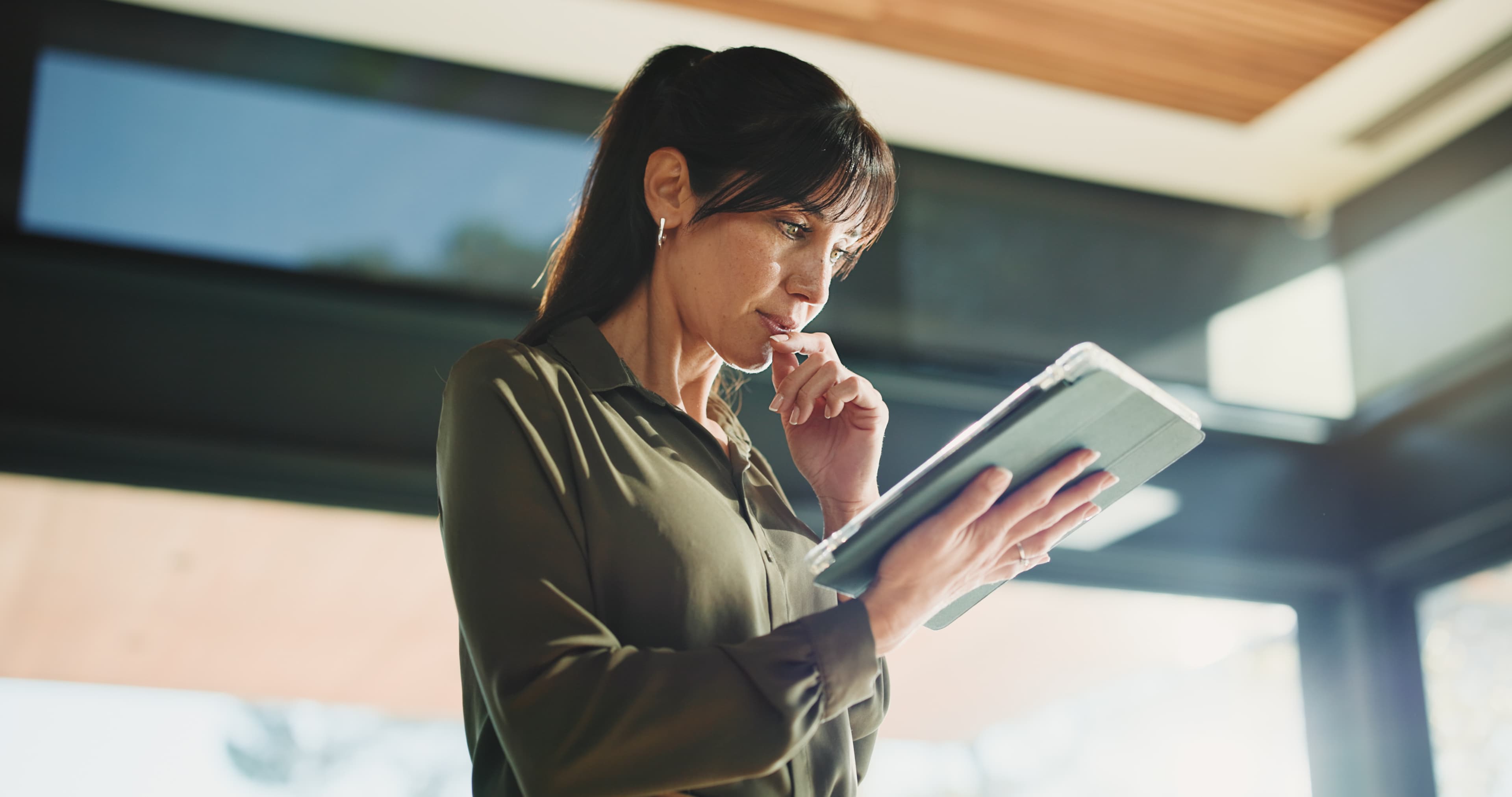 woman thoughtfully reviews content on a tablet AdobeStock 1787092644