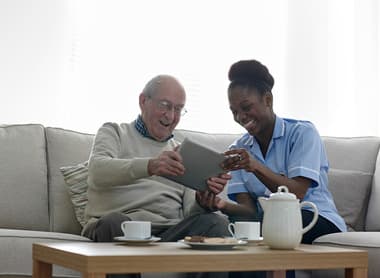 Happy senior man and nurse using digital tablet