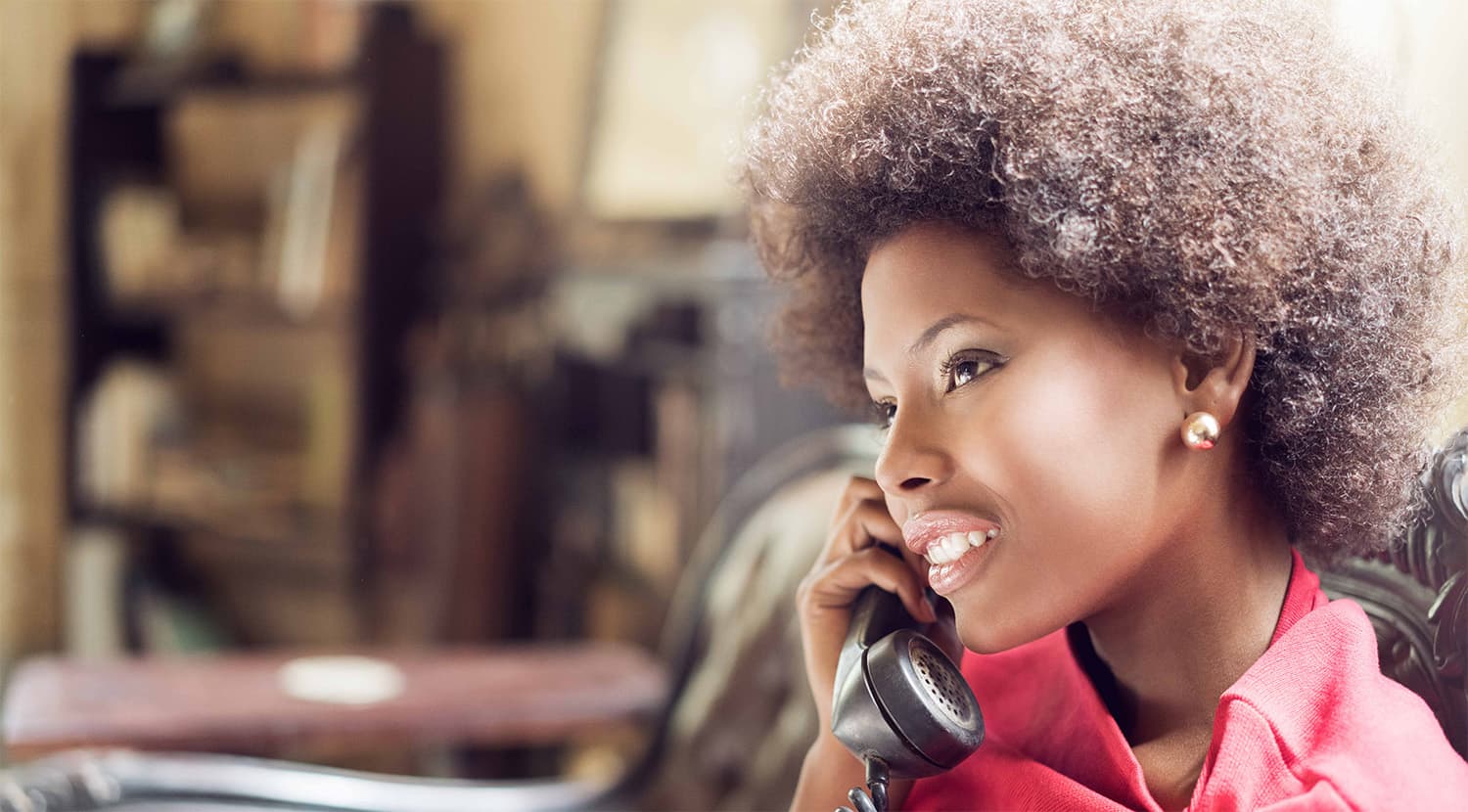 Young woman smiling whilst speaking on a landline telephone handset