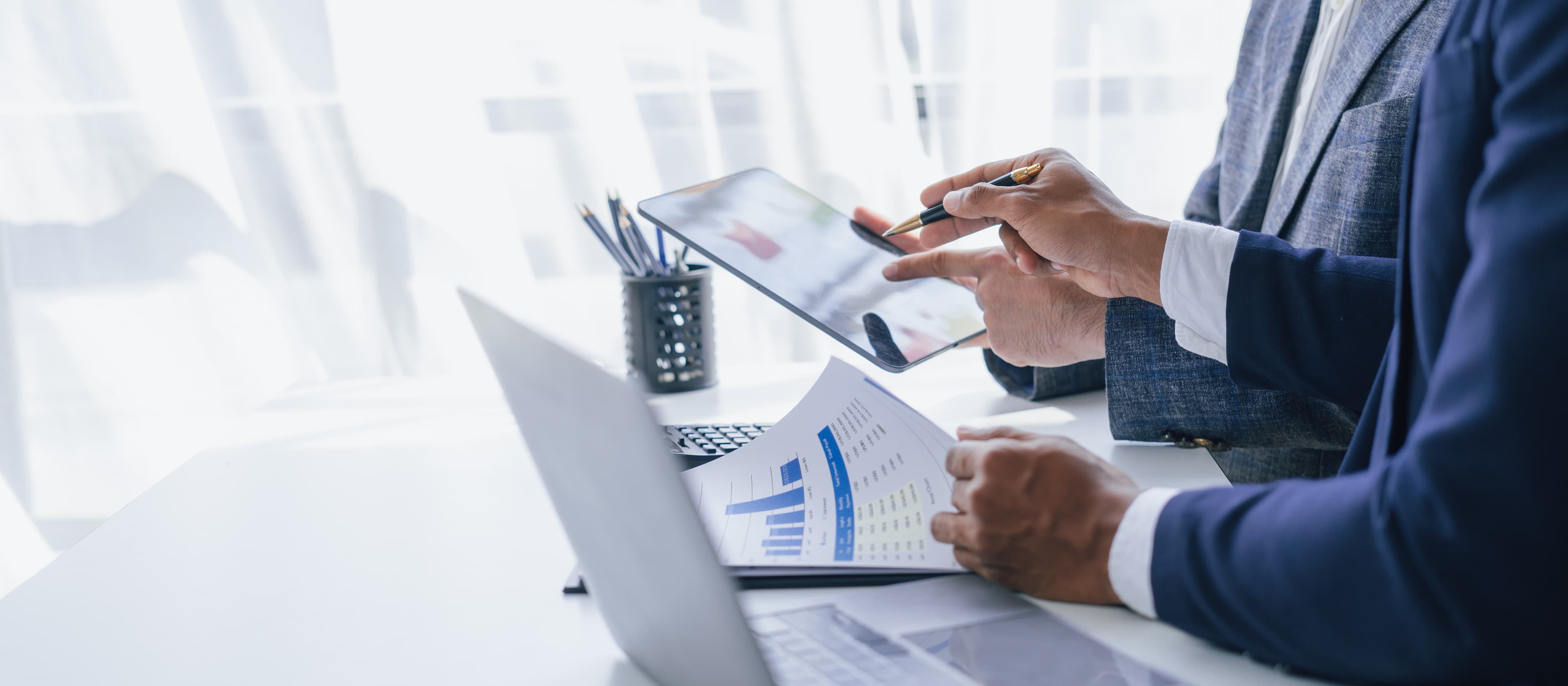 Two professionals reviewing business data charts alongside a laptop and tablet, illustrating practical AI adoption planning